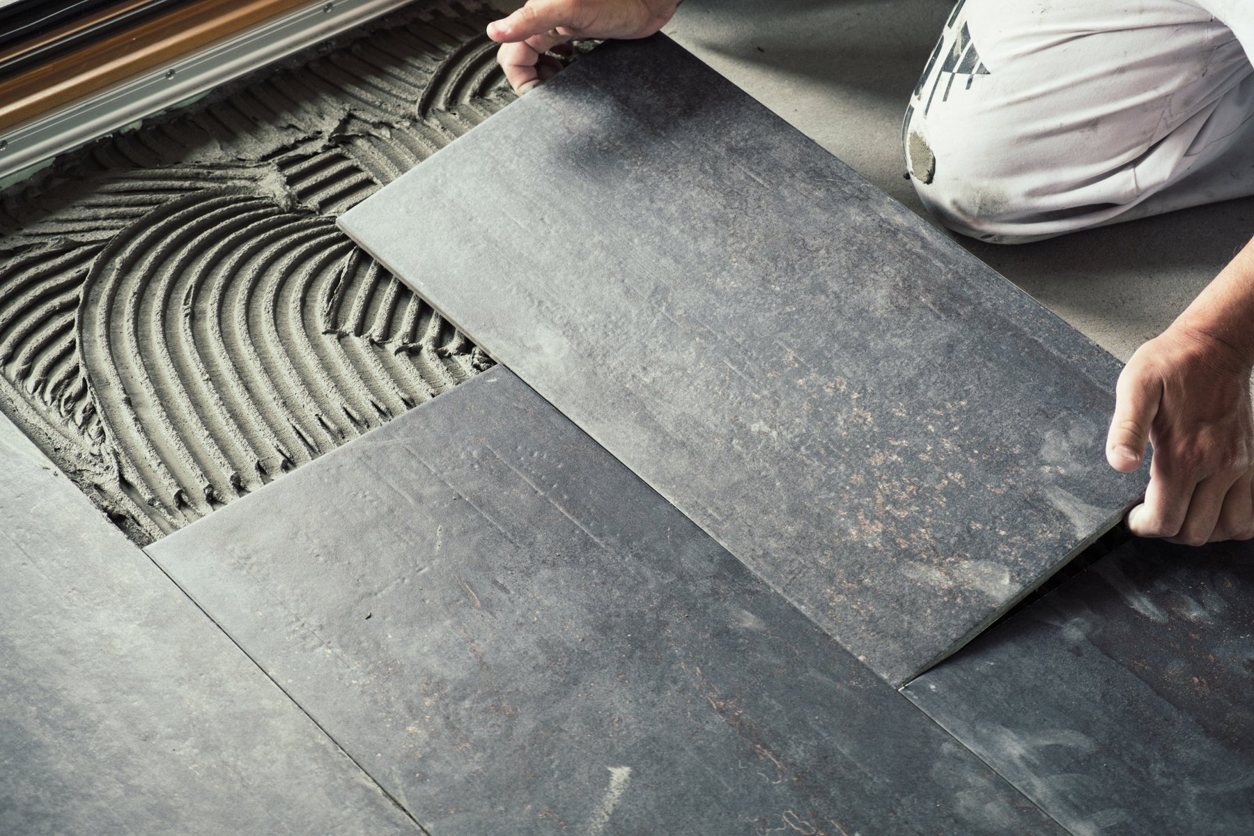 Worker placing ceramic floor tiles